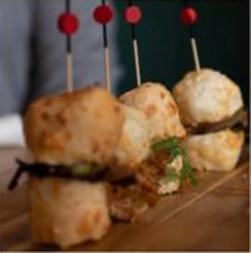 Mini hamburguesa montada con dos panes de yuca y pinchos de colores